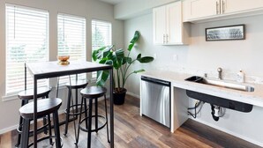 A kitchen with a wooden table, bar stools, a dishwasher, and a sink. - Tacoma Dome condo w Mountn & Bay views + + PRK! (Tacoma)