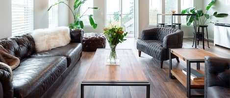 A modern living room with leather sofas, a coffee table, and potted plants.