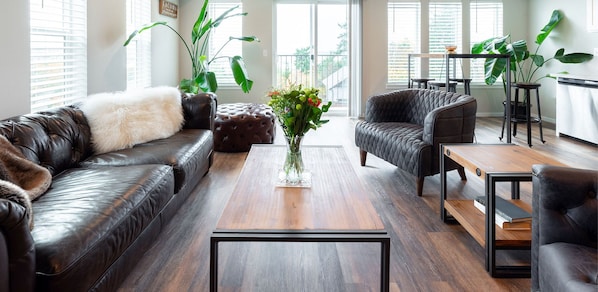 Una sala de estar moderna con sofás de cuero, una mesa de centro y plantas en macetas.