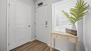 A hallway with white doors, a wooden console table with a sign, and a potted plant. - Steps to Dome Breathtaking views + parking + AC! (Tacoma)