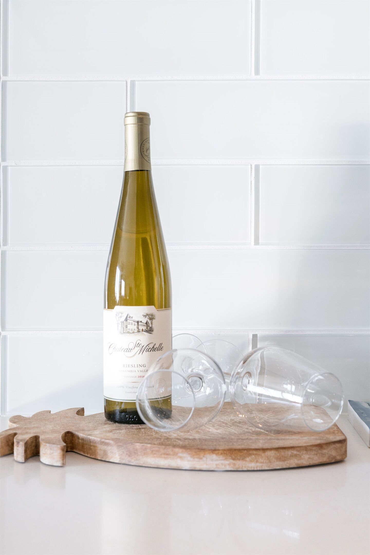 Una botella de vino sobre una tabla de madera con copas y corchos.