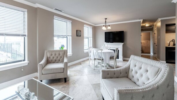 A spacious living room with a fireplace, a dining area, and a kitchen visible through an open doorway.
