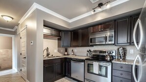 A modern kitchen with dark cabinetry, stainless steel appliances, and a granite countertop.