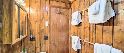 A wooden-paneled bathroom with a sink, mirror, and towel rack.