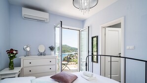 Un dormitorio con cama, mesitas de noche, cómoda, espejo y vistas a un balcón con silla y mesa.