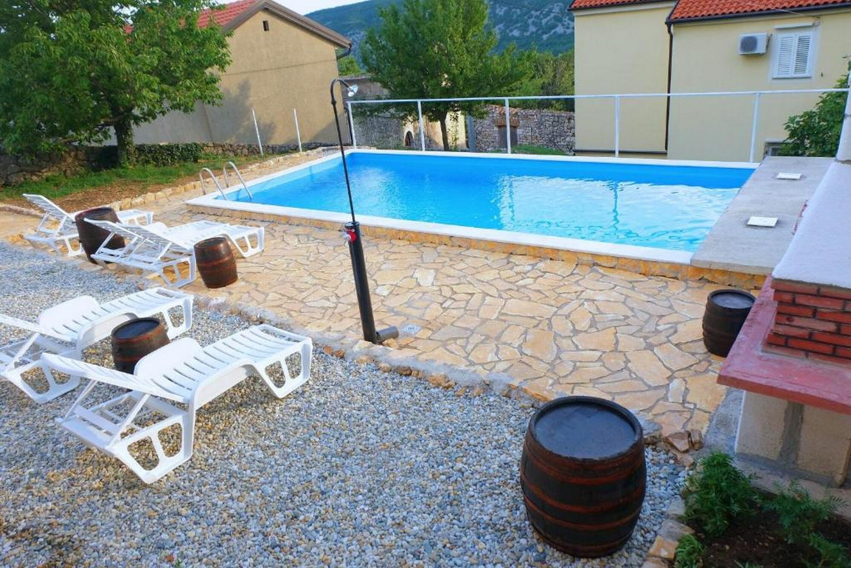 Ein Schwimmbecken mit weißen Liegestühlen und einer Steinterrasse.