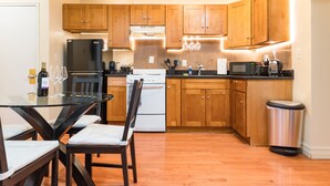 Una cocina moderna con armarios de madera, una mesa de comedor de vidrio y electrodomésticos de acero inoxidable.