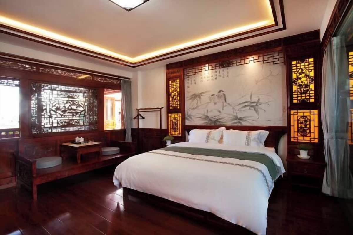 A traditional room with a large bed, wooden furniture, and decorative screens.