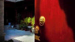 A red door with a golden lion head knocker and a padlock. - Yamingyuan Inn (Dali City)