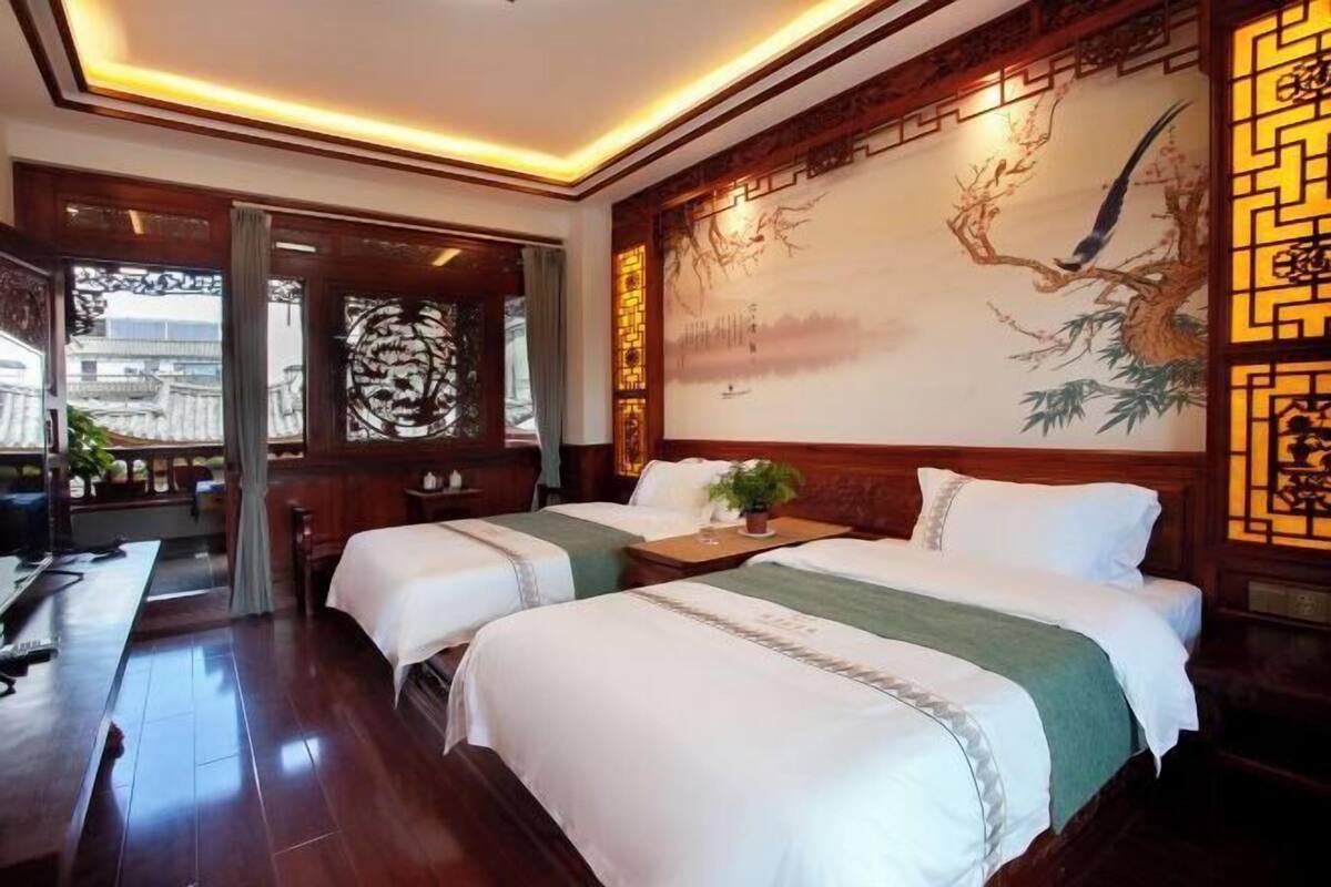 A hotel room with two beds, a large mural, and traditional decor.