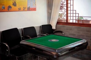 A pool table with four chairs, a brick wall, and a window with curtains. - Yamingyuan Inn (Dali City)