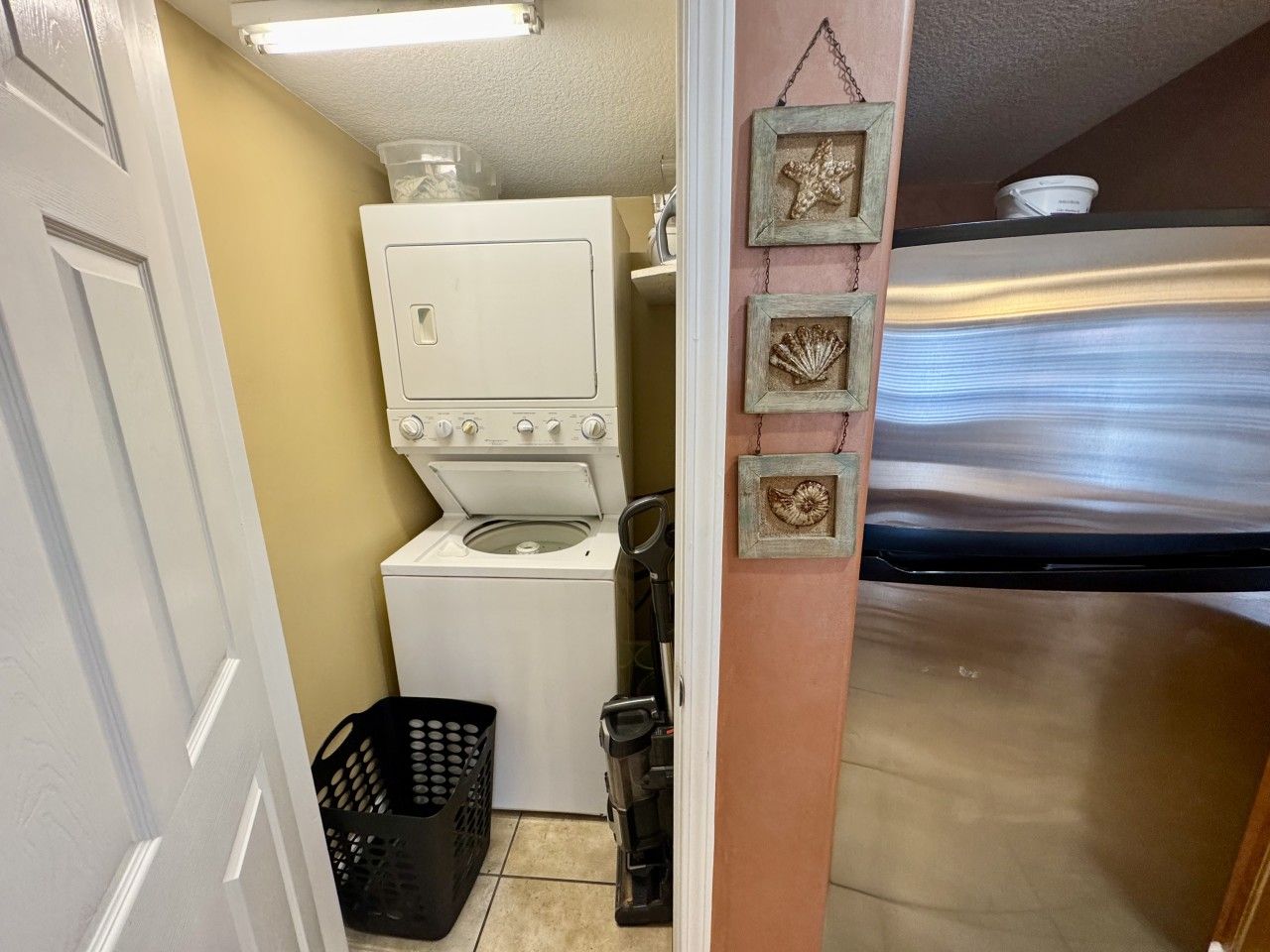 A laundry room with a washing machine, a dryer, and a small trash bin.
