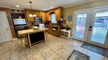 A kitchen with wooden cabinets, a built-in microwave, and a dining area with a bench.