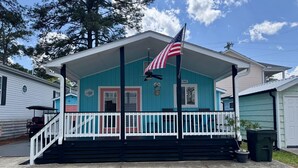 Une maison à deux étages avec un porche, un drapeau et une boîte aux lettres.