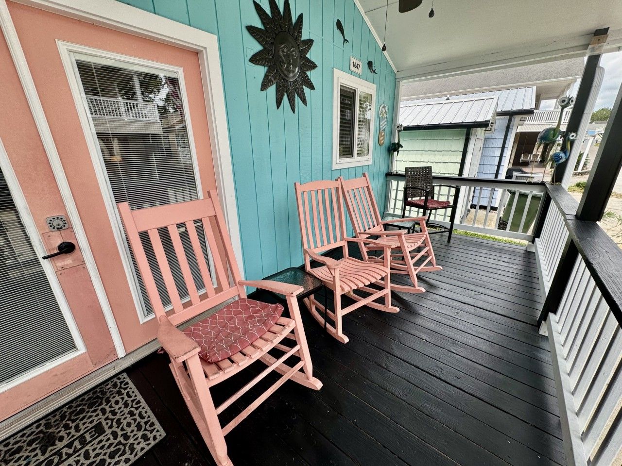 A porch with wooden chairs and a decorative wall piece.