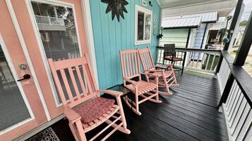 A porch with wooden chairs and a decorative wall piece.