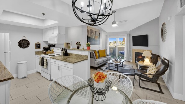 A modern kitchen with white cabinets, a central island, and a dining area with a glass table and chairs.