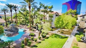 A resort with a swimming pool, palm trees, and a large building in the background.