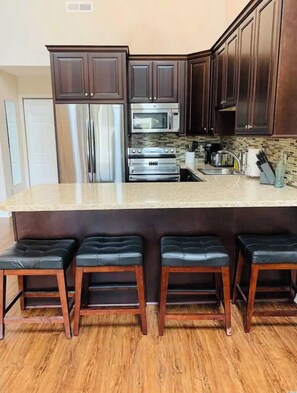 Kitchen features a large island with a countertop and four bar stools.