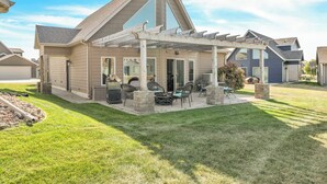 A house with a covered patio area featuring outdoor furniture and a grill.