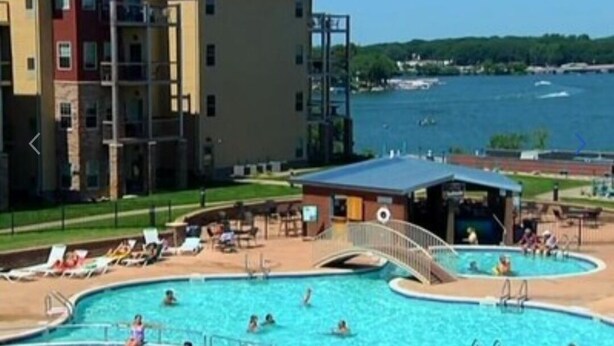 A hotel with a swimming pool, a covered area, and a view of the water.