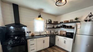 A modern kitchen with a stainless steel refrigerator, black stove, white cabinets, and a wooden floor. - 7 mi to Grand Park, 1 mi to Mustard Seed, 5 min to downtown Noblesville! (Noblesville)