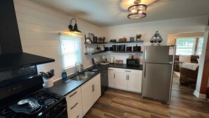 A modern kitchen with white cabinets, a stainless steel refrigerator, and a black stove.