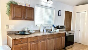 A kitchen with wooden cabinets, a granite countertop, a stainless steel sink, and a built-in oven. - The Mushroom Patch Cabin (Union)