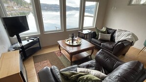 A living room with a leather sofa, a wooden coffee table, and a TV on a stand. - The Mushroom Patch Cabin (Union)