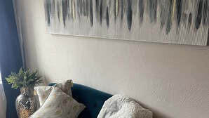 A teal sofa with two pillows, a white throw blanket, and a decorative vase with plants. - The Mushroom Patch Cabin (Union)