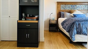 A bedroom with a bed, a nightstand, a dresser with open cabinets, and a wall with a mosaic pattern. - The Mushroom Patch Cabin (Union)