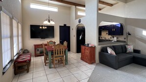 Una sala de estar con comedor, televisor y cocina con armarios oscuros.
