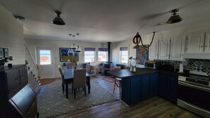 A spacious kitchen with a central island, a dining area with a table and chairs, and a large window providing natural light.