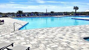 Un espace piscine avec des chaises longues et un ciel dégagé.