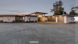 Uma casa moderna de dois andares com amplo acesso por carro, garagem e jardim frontal bem cuidado.