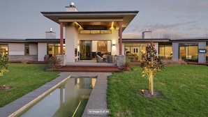 Uma casa moderna com varanda coberta, piscina e gramado bem cuidado.