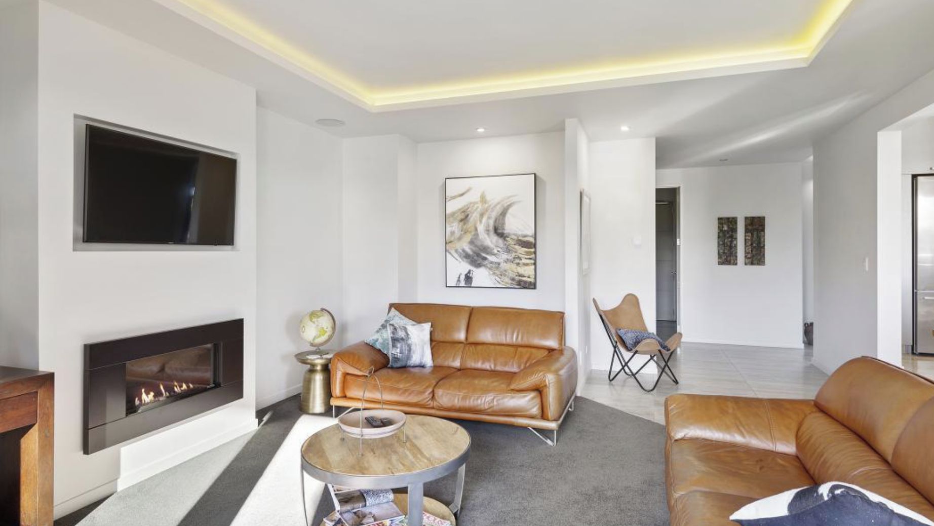 A modern living room with a fireplace, leather sofas, a coffee table, and artwork on the walls.