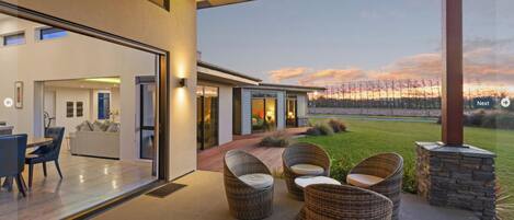 A modern house with a spacious patio, a dining area, and a view of the landscape.