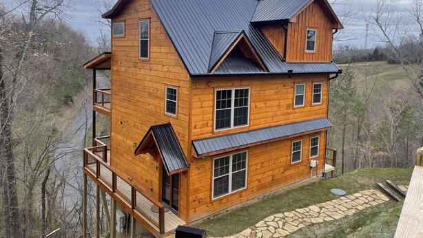 A multi-story wooden house with a metal roof, a deck, and a stone pathway. - New Built 2023- upscale, central location, Indoor pool (Pigeon Forge)