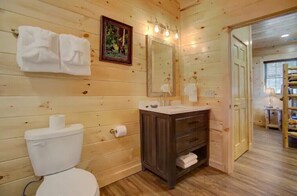 Ein Badezimmer mit Holzwandverkleidung, Toilette, Waschbecken und Spiegel.