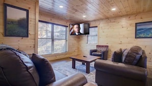 A cozy living room with a wooden ceiling, a television mounted on the wall, and two leather sofas. - New Built 2023- upscale, central location, Indoor pool (Pigeon Forge)