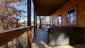 A wooden deck with a hot tub, wooden railing, and a view of trees. - New Built 2023- upscale, central location, Indoor pool (Pigeon Forge)