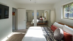 Una camera da letto con un letto grande, una TV fissata al muro e una finestra vista all'esterno.