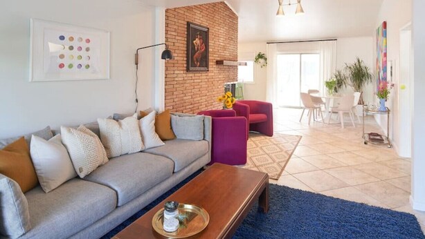 Un soggiorno moderno con un divano grigio, un tavolino in legno e una parete decorata in mattoni.