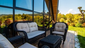 Eine Terrassenfläche mit Korbmöbeln und Blick auf einen angelegten Garten.