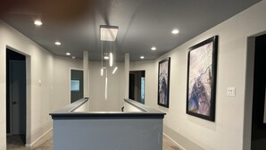 A modern hallway with a central island, recessed lighting, and framed artwork on the walls.
