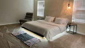A bedroom with a bed, a chair, a ceiling fan, and a rug.