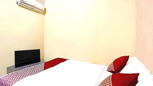 Una habitación de hotel con una cama, un televisor de pantalla plana y un aire acondicionado en la pared.