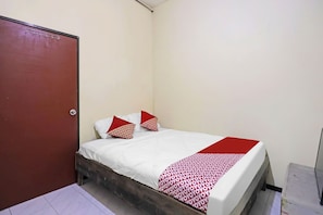 A small, single-bed room with a wooden headboard, white bedding, and a red and white patterned throw blanket. - Spot On 91343 Kartika Guest House Syariah (Batam)