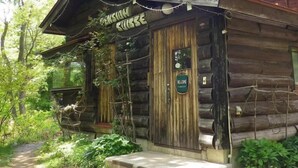 A rustic log cabin with a welcoming sign, a wooden porch, and a path leading to the entrance. - Pension Swiss (Kaminoyama)